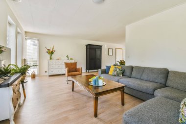 Odanın ortasında kanepeleri, sehpası ve televizyonu olan bir oturma odası beyaz duvarlarla çevrili.