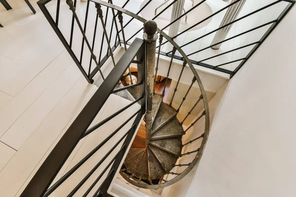 a spiral staircase in a modern house, taken from the top down to the floor below its black and white railings