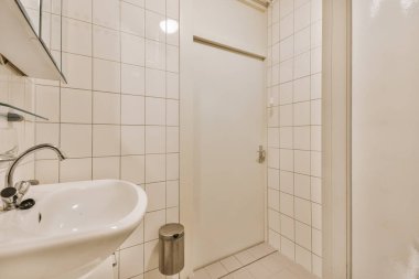 Yanındaki duvarda lavabo ve ayna olan banyo birkaç yıldır kullanılmakta olan bir duş kabini.