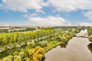 Arka planda ağaçlar ve binalar olan nehir güneşli bir yaz gününde hava aracının kamerasından alındı.
