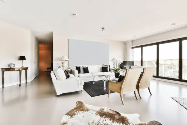 a living room with white furniture and cow skin rugs on the floor in front of the couch, looking out to the balcony