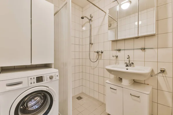 a laundry room with a washer and dryer on the wall, in front of a mirror above it