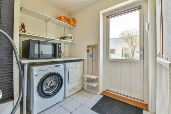 a laundry room with a washer, dryer and microwave on the wall in the photo is taken from inside