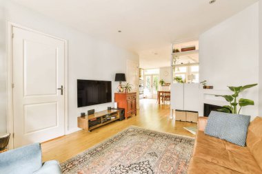 Kanepenin önündeki duvarda kanepe ve televizyon olan bir oturma odası doğu halısıdır.