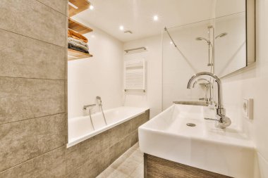 Küvetin yanında lavabosu, aynası ve küveti olan bir banyo.