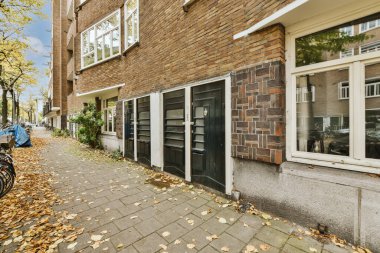 Beyaz ve siyah kapılı tuğla bir binanın önünde caddenin kenarına park etmiş bir bisiklet.