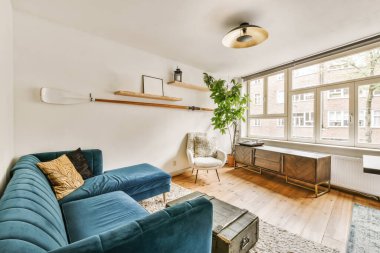 Mavi kanepeleri olan bir oturma odası ve köşesinde bir televizyon seti olan bir sehpa.