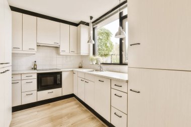 Bu modern tarzdaki evdeki dolapların üzerinde beyaz dolaplar ve siyah süslemeler olan bir mutfak çok temizdir.