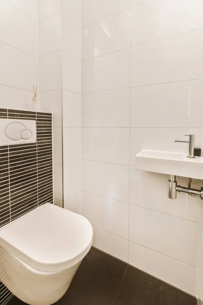 a modern bathroom with black and white tiles on the walls, toilet and sink in the room is clean and ready to use
