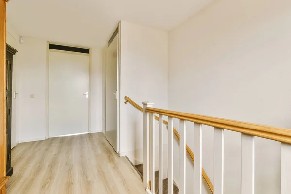 an empty room with white walls and wood railings on the bottom floor, there is a wooden staircase leading up to the second
