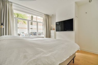 Büyük yataklı bir yatak odası ve odanın duvarına monte edilmiş düz ekran bir televizyon çok temiz.