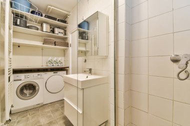 Köşesinde çamaşır makinesi ve kurutma makinesi olan küçük bir çamaşır odası.