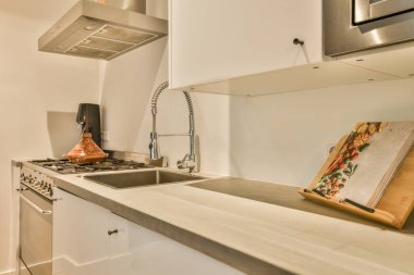 Tezgahta beyaz bir mutfakta fırını olan ve arkasında lavabo olan bir tablo tahta kesme tahtasıdır.