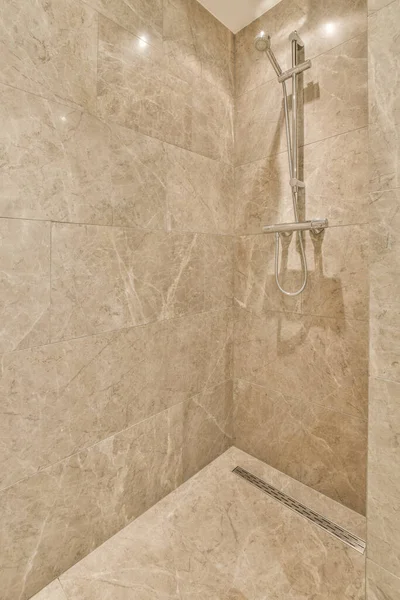 a bathroom with marble walls and shower head mounted to the wall, its not clear in this photo
