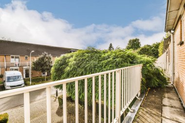 Evin önünde ağaçlar ve çalılar büyüyen bir evin önünde beyaz bir çit var.