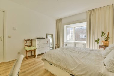 Yatağı, masası ve penceresi olan bir yatak odası. Arka tarafta mobilyası olmayan bir oda.