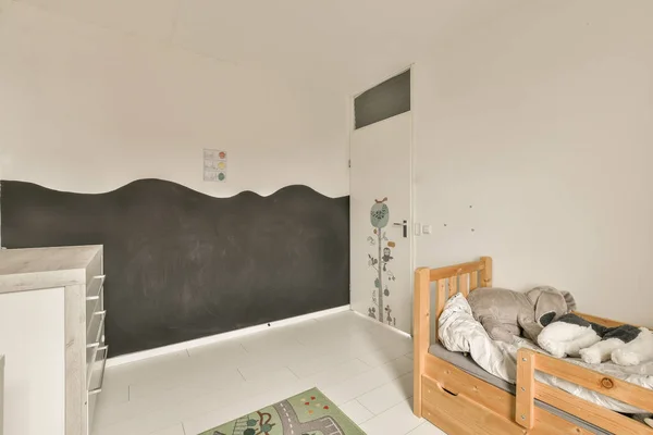 a childs room with a chalkboard on the wall and a bed in front of a blackboard