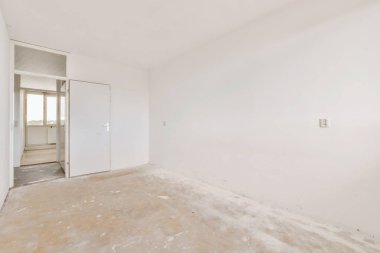 Beyaz duvarları olan boş bir oda ve diğer duvarda hiç kapı yok. Köşede bir pencere var.