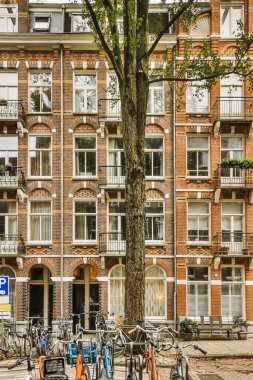 Caddenin kenarında birçok pencere ve balya olan bir apartmanın önüne parketmiş bisikletler.