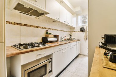 Tezgahın üzerinde beyaz dolaplar ve ahşap tezgah olan bir mutfak açık bir kapıdan alınır.