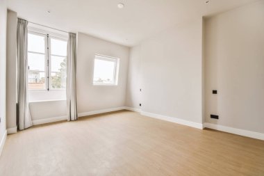 Odasında ahşap döşeme ve beyaz duvarlar olan boş bir oturma odası çok temiz, ama mobilya yok.