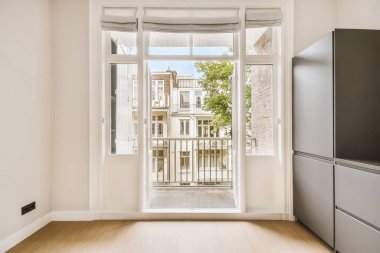 Boş bir mutfak. Kapısı açık. Bahçeye ve bahçeye bakan bahçeler var.