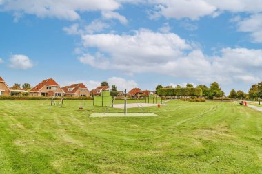 Arka planda evleri ve mavi gökyüzü fotoğrafı olan boş bir park - 12309783 JPD