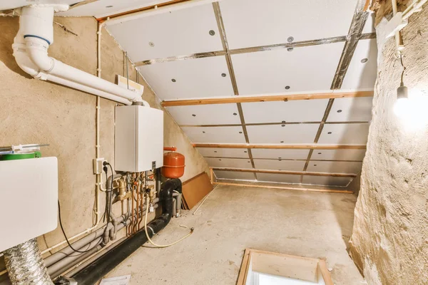 a room under construction with pipes and water heater in the corner, which is being used for plumbing work