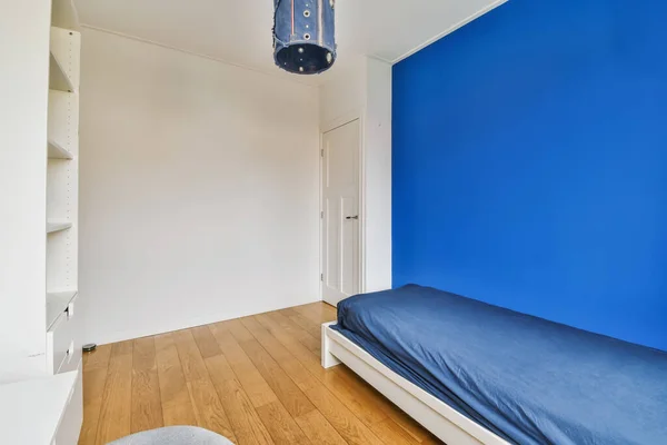 a bedroom with blue walls and wood flooring, including a single bed in the corner of the room to the left is a