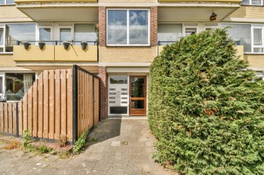 Ön bahçesinde ağaçlar ve çalılarla çevrili iki katlı bir evin dış görünüşü.