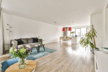 Beyaz duvarları ve ahşap döşemeleri olan bir oturma odası. Odanın ortasında büyük ahşap bir sehpa da var.