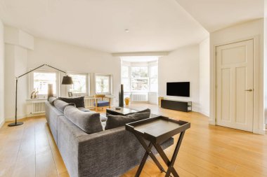 a living room with hardwood flooring and white walls in the center of the room is a couch, coffee table, tv stand