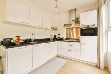 Bu odadaki tezgahların üzerinde beyaz dolaplar ve siyah tezgahlar olan bir mutfak çok temiz, ama öyle değil.