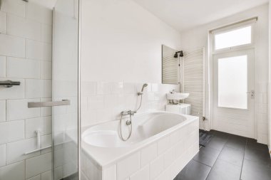 a bathroom with black and white tiles on the walls, floor, and bathtub in its corner