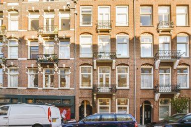 an apartment building with cars parked on the street next to it and people walking down the sidewalk in front of them
