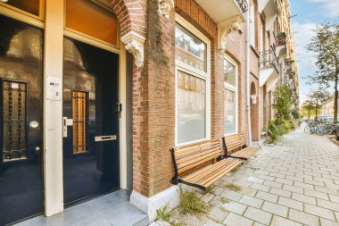a brick building with two doors on the front and an open door to the other side of the building there is a blue sky