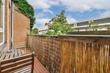 an outside area with wood fence and green plants on the side of the building, looking out onto the street