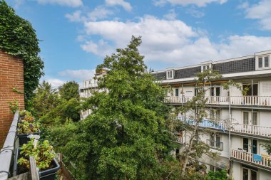 an apartment building with trees and bushes in the foreground area on a bright sunny day, taken from above
