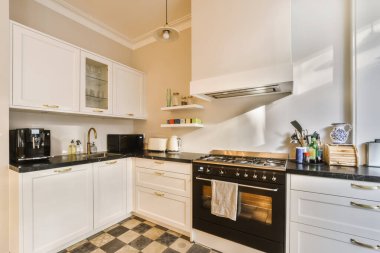 a kitchen area with black and white tiles on the floor, sink, stove, oven and dishwasher