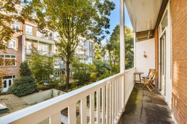 an outside area with trees and houses in the background, as seen from a balcony on a sunny summer day