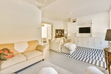 Odadaki duvarda iki kanepesi ve düz ekran televizyonu olan bir oturma odası çok temiz.