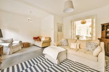 a living room with striped rugs on the floor and white couches in the center of the room,
