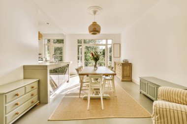 a living room with a dining table and two couches in front of the window looking out onto the garden