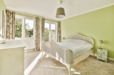 a bedroom with green walls and white furniture in the corner, including a bed that is next to a window