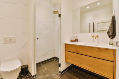 a modern bathroom with marble flooring and white walls, along with a wooden cabinet under the sink is next to the toilet