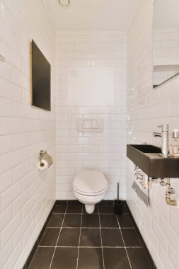 a bathroom with black and white tiles on the floor, sink, toilet, and mirror in its corner