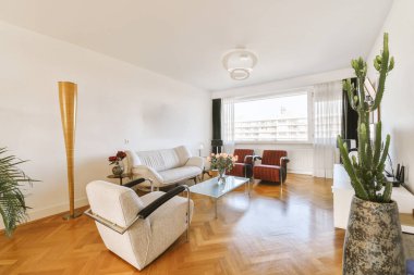 a living room with wood flooring and plants in the vases on the coffee table next to the couch