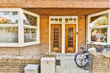 a brick house with a bicycle parked in the front door and two windows on the side of the house,