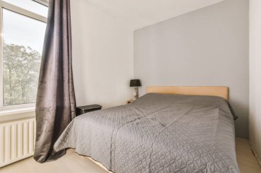 Odanın sağ tarafında yatak odası, pencere ve lamba olan beyaz duvarlar var.