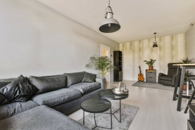 Salonun ortasında gri koltukları ve siyah sandalyeleri olan bir oturma odası küçük bir yemek masası.